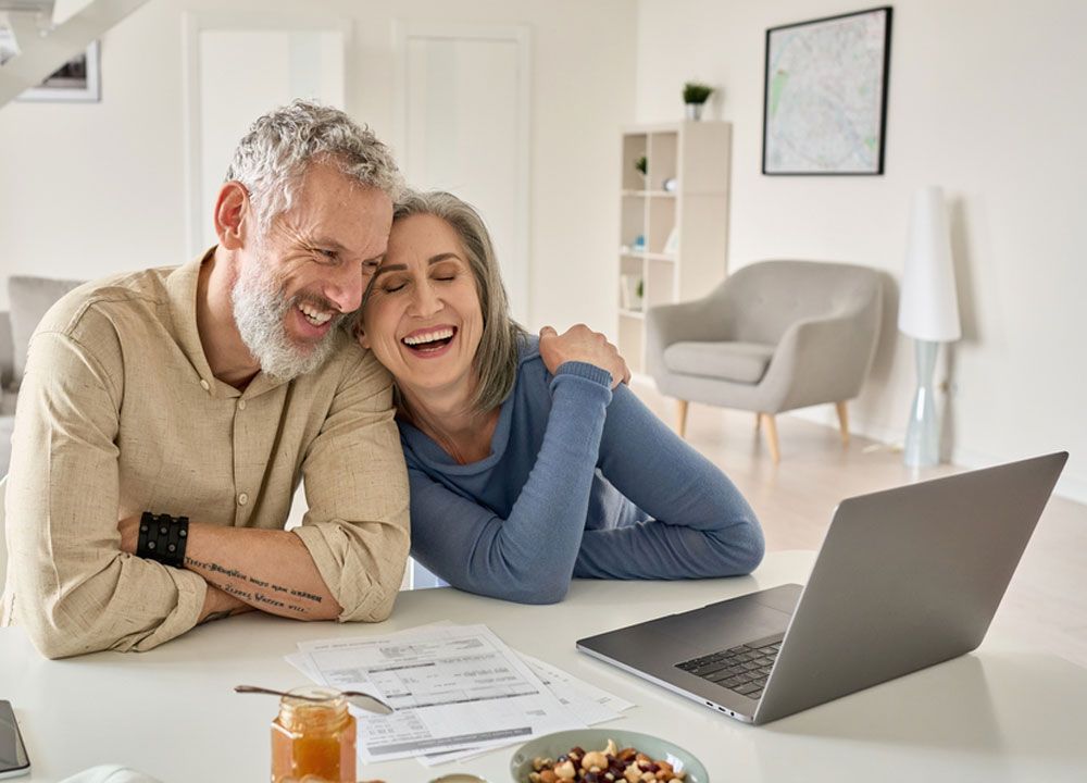 A man and a woman are sitting at a table with a laptop.