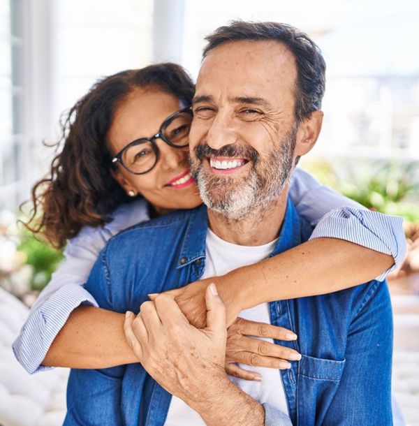 A man is hugging a woman who is holding a cup of coffee.