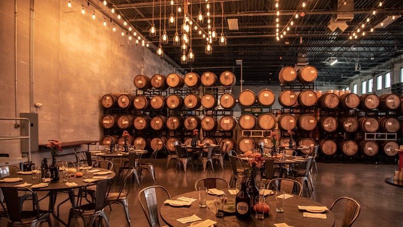 A large warehouse filled with lots of barrels and tables.