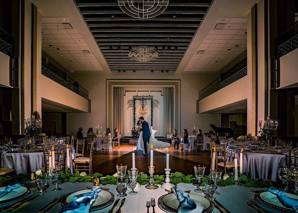A bride and groom are dancing in a large ballroom.