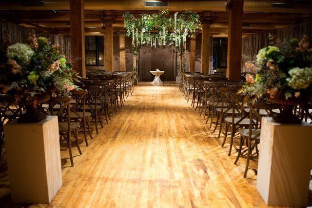 A large room with wooden floors and chairs set up for a wedding ceremony.