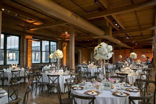 A large room with tables and chairs set up for a wedding reception.