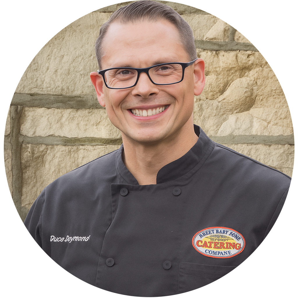A man in a chef 's uniform is smiling in front of a brick wall