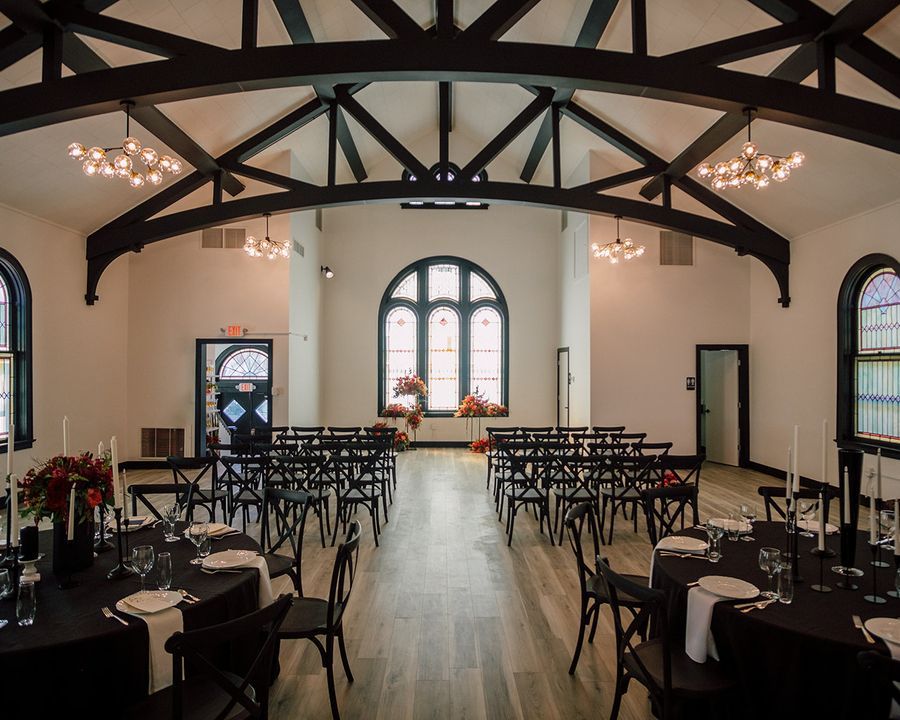 A large room with tables and chairs set up for a wedding ceremony.