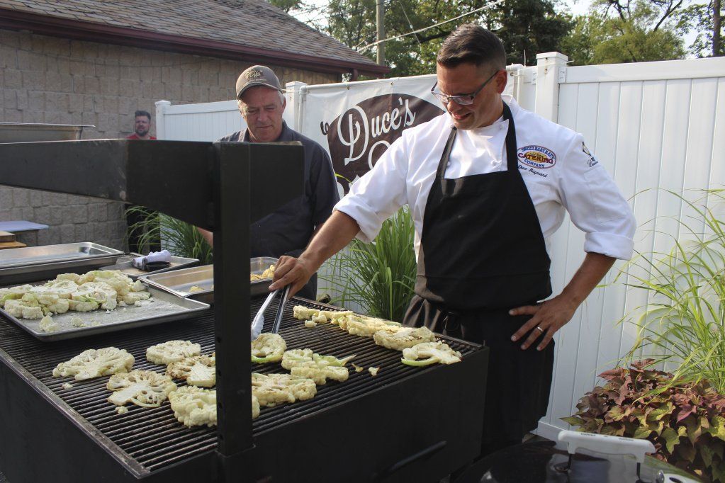 A man is cooking food on a grill in a backyard.