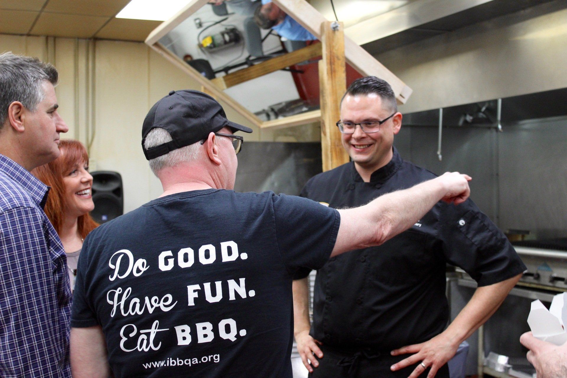 A man wearing a shirt that says do good have fun eat bbq