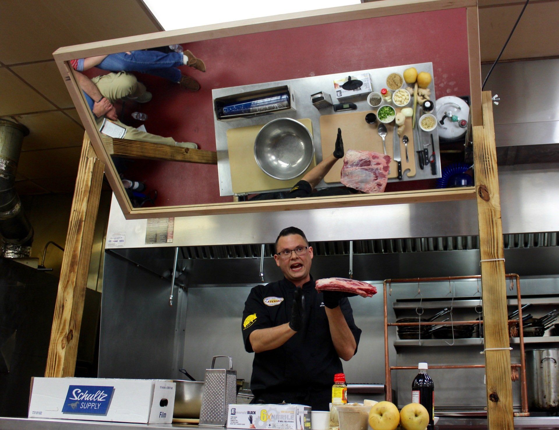 A man is standing in a kitchen holding a piece of meat