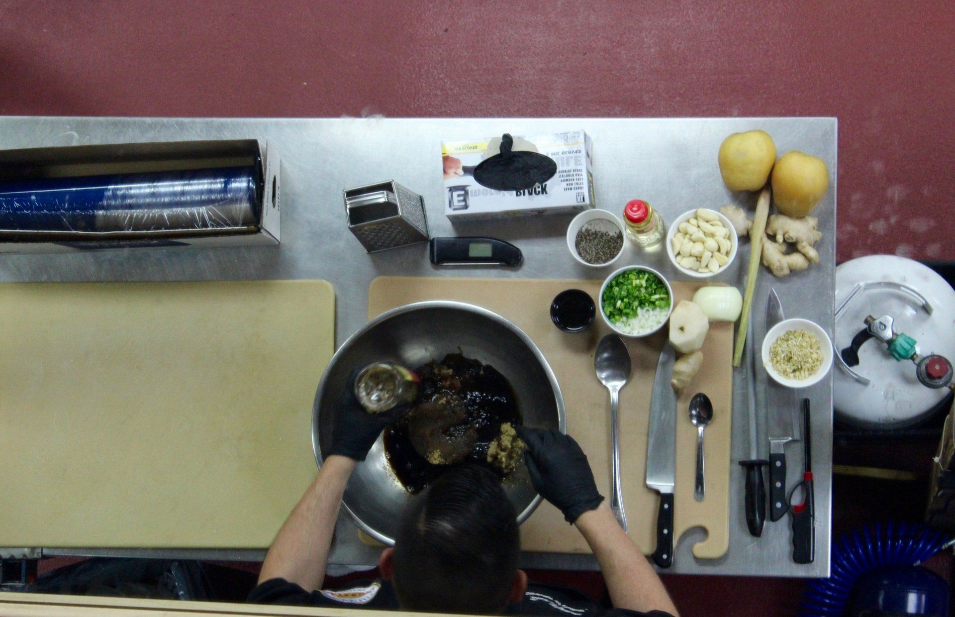 A person wearing black gloves is preparing food on a table
