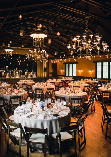 A large room with tables and chairs set up for a wedding reception