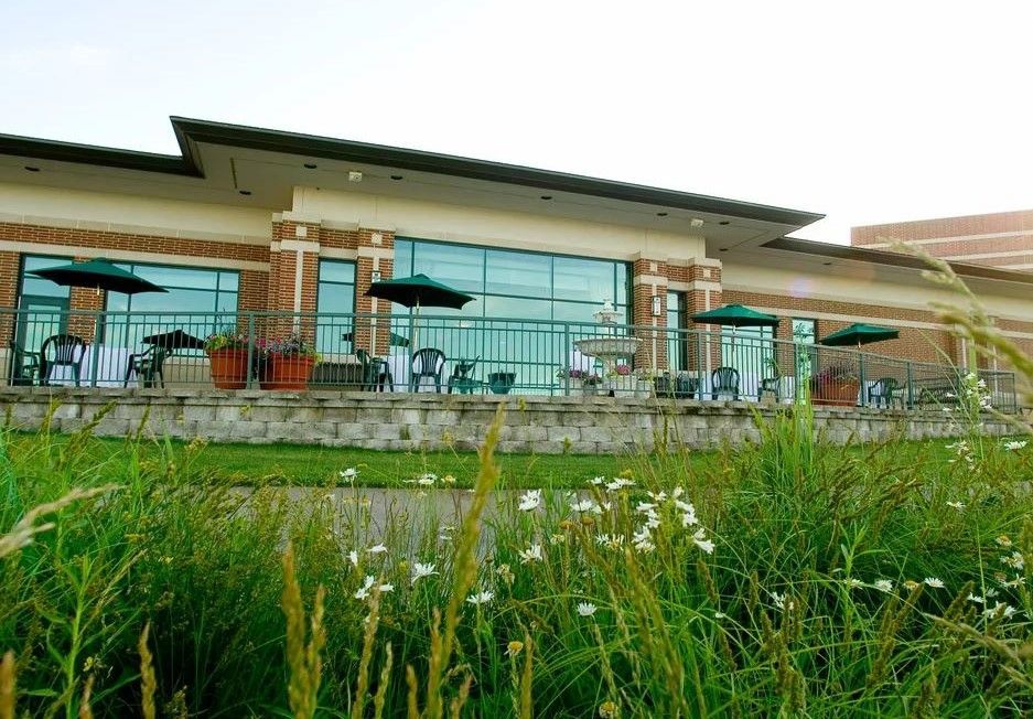 A large building with tables and chairs and umbrellas in front of it