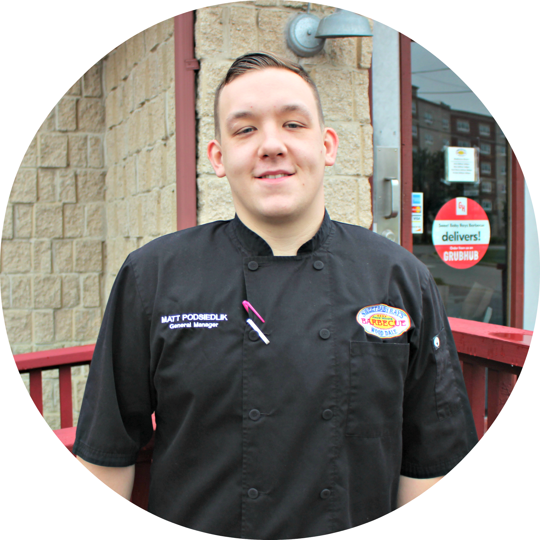 A man in a chef 's uniform stands in front of a building