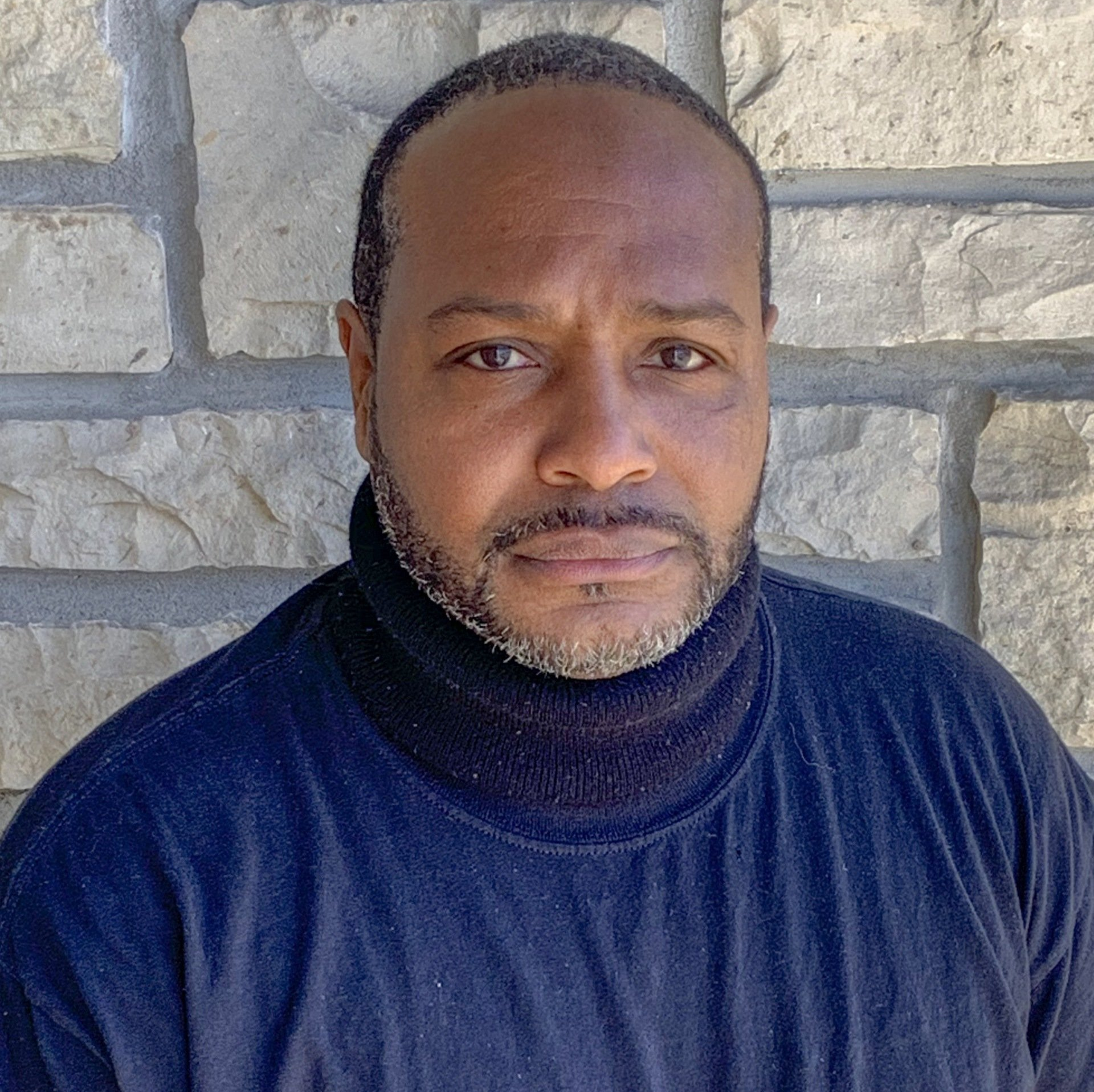 A man with a beard is wearing a black turtleneck sweater