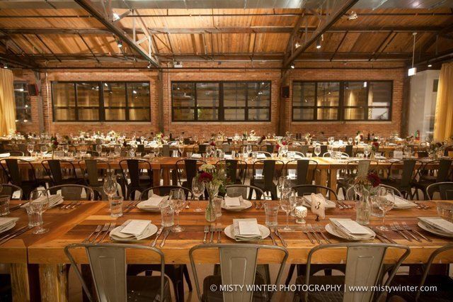 A large room with tables and chairs set up for a wedding reception