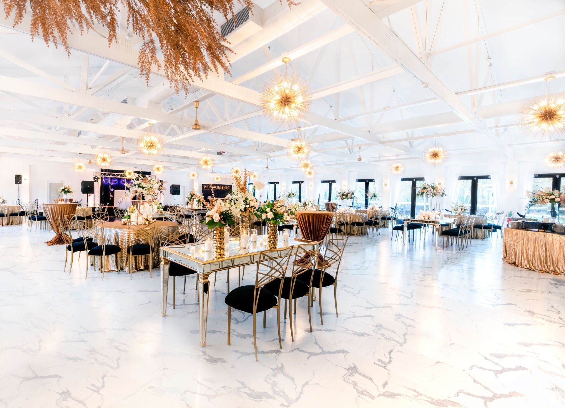 A large room with tables and chairs set up for a wedding reception.