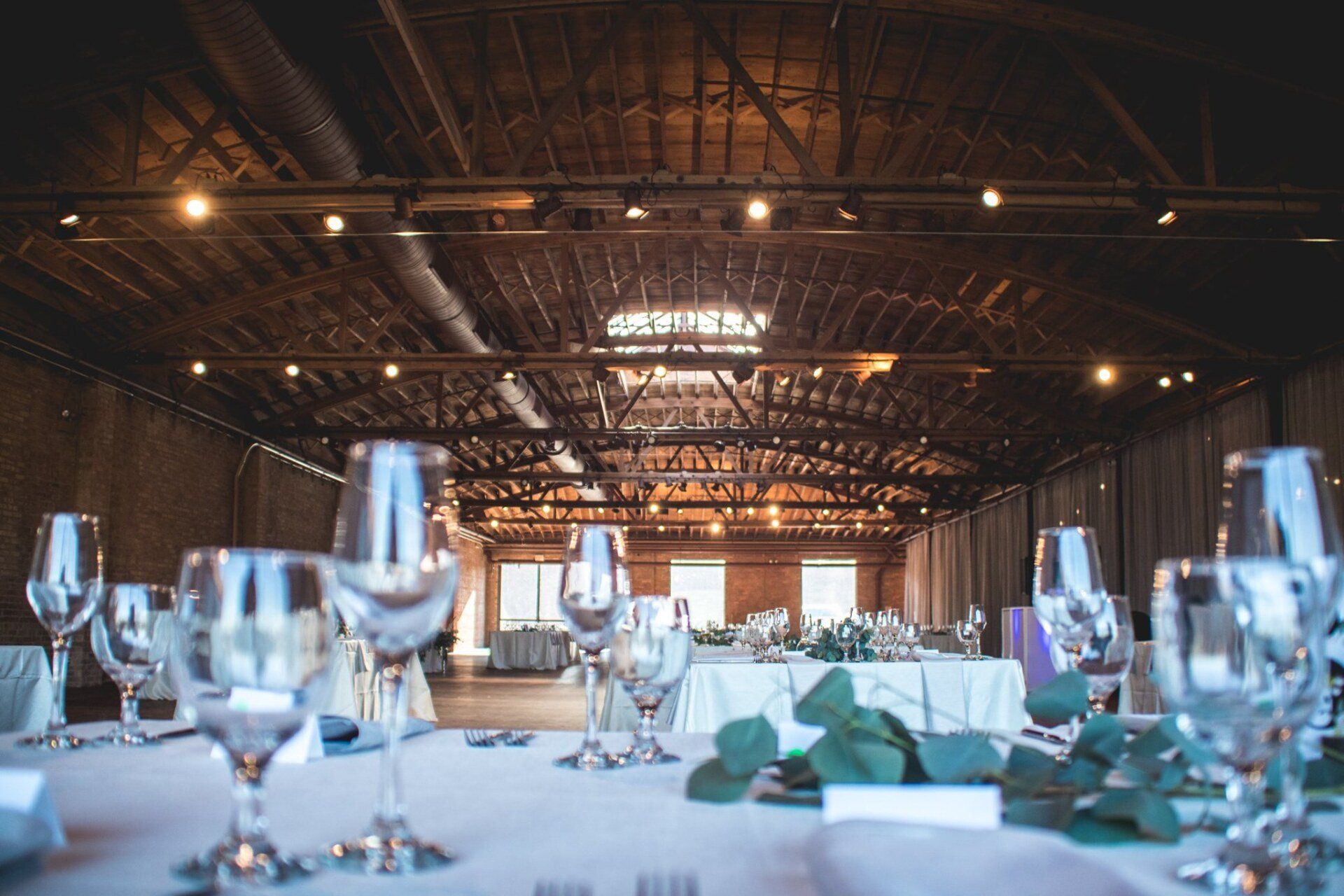 A table set for a wedding reception with wine glasses on it.