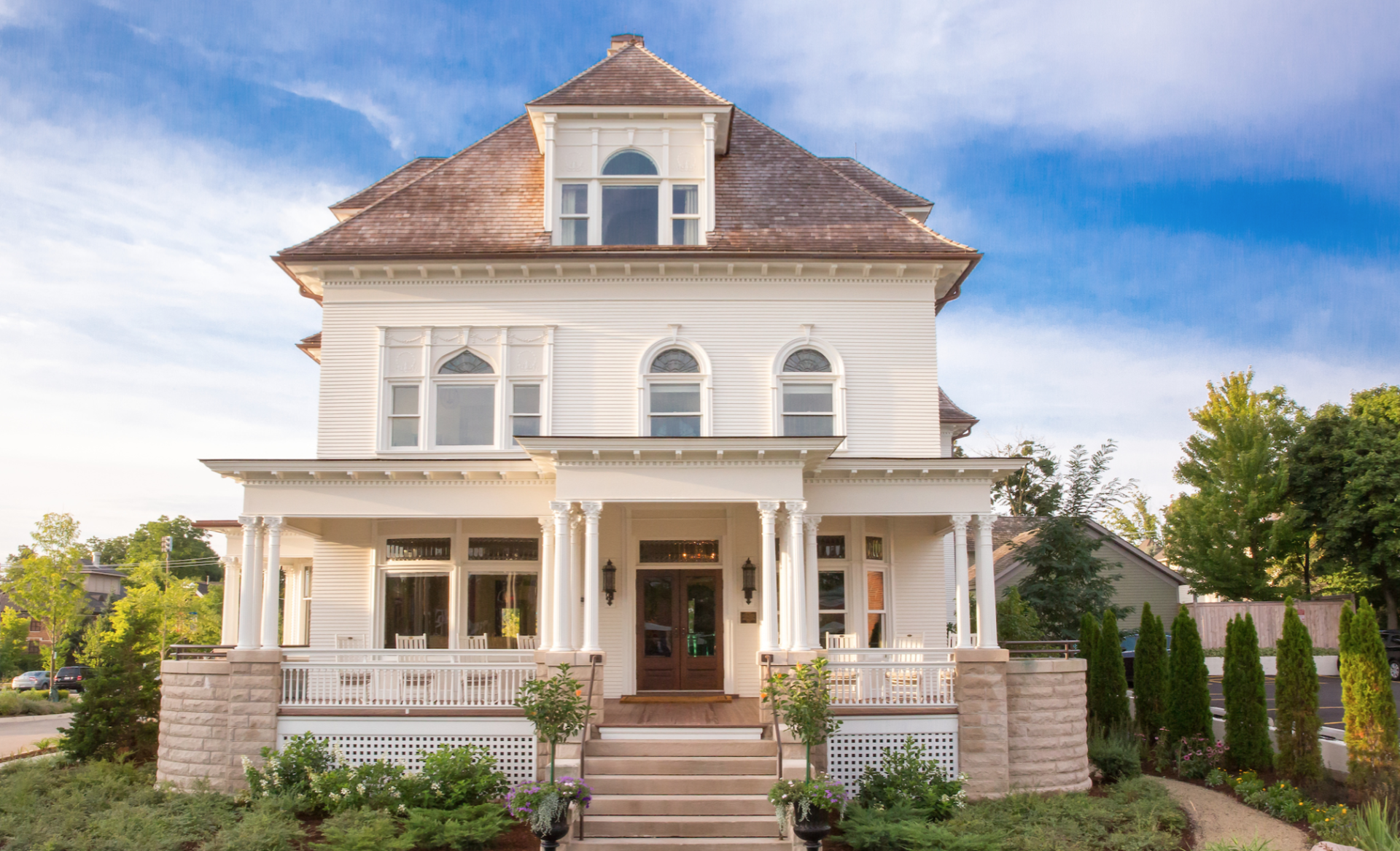 A large white house with a porch and stairs in front of it.