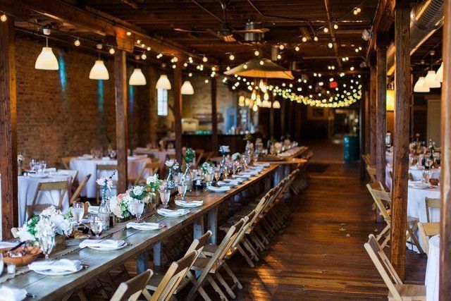 A wooden loft with farm tables and large windows.