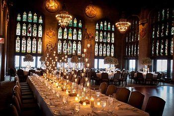 A long table with candles on it in a room with stained glass windows.