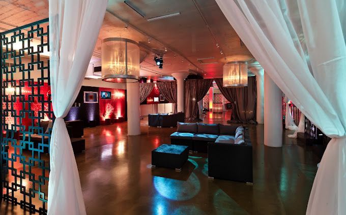 A room with couches, chandeliers, uplights, and draping.