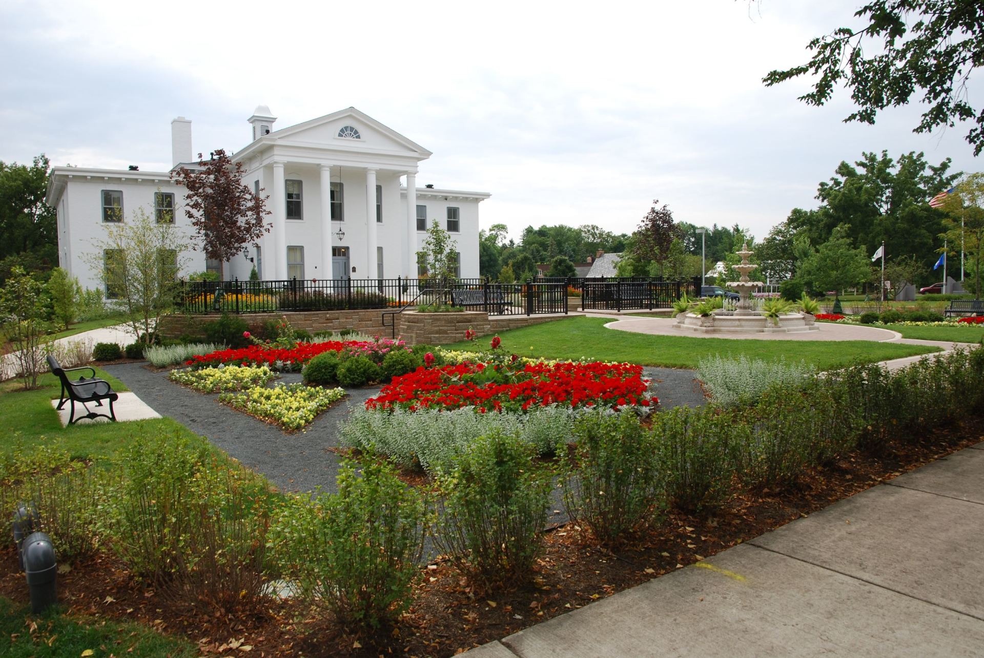A large white house sits in the middle of a park
