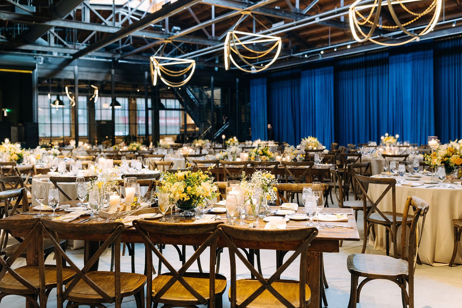 A large room with wooden chairs, flowers, and chandeliers.