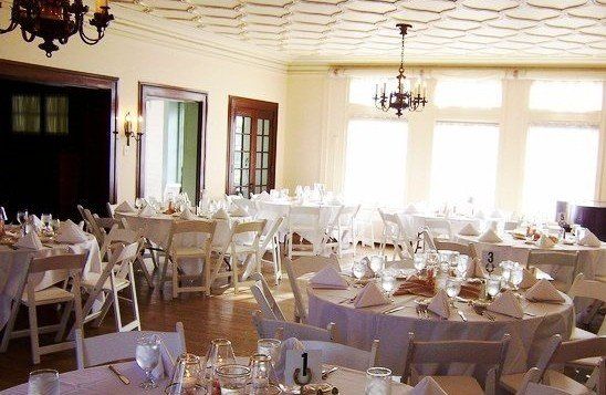 A large room with tables and chairs set up for a wedding reception.