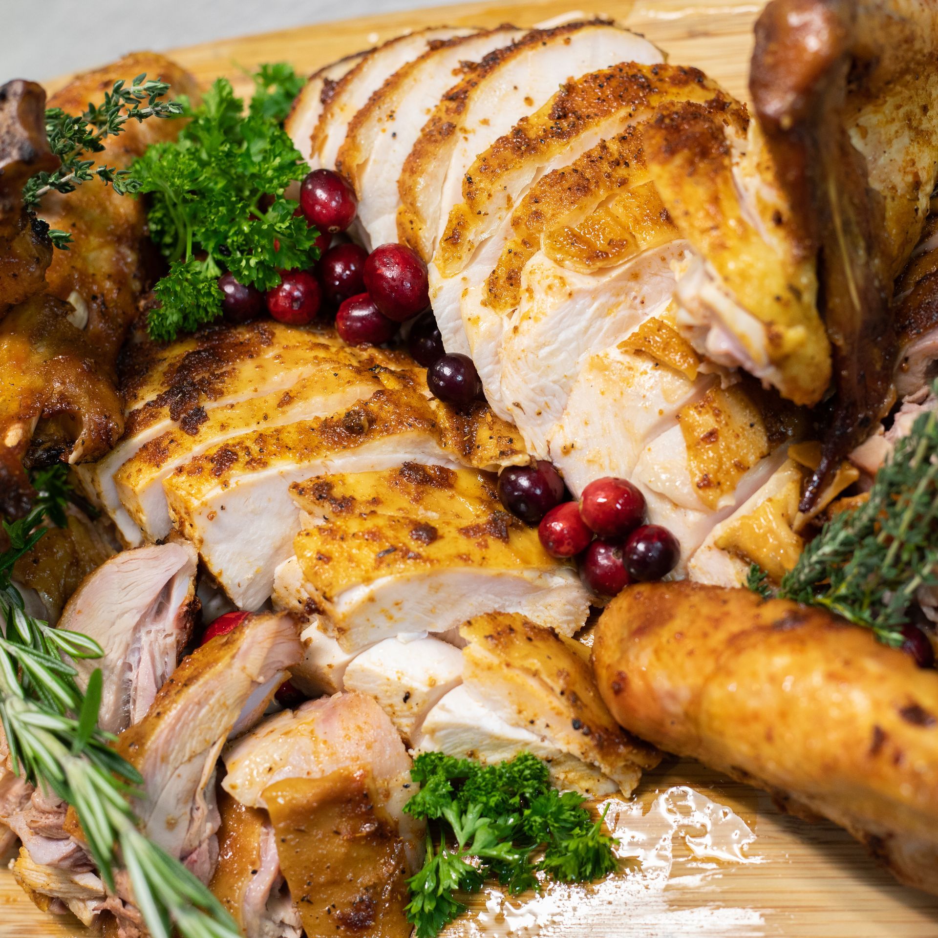 sliced turkey with cranberries and parsley and rosemary garnish