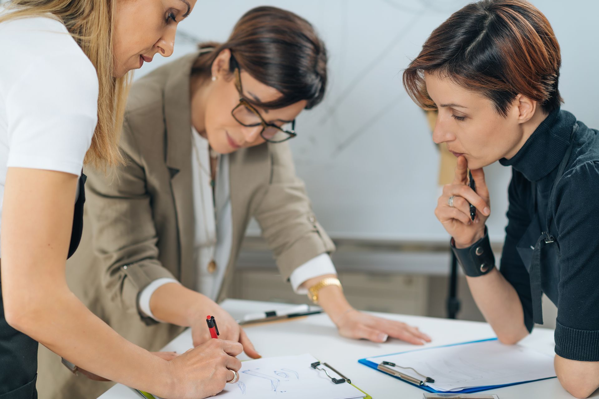 Three women in office, looking at documents and working together.