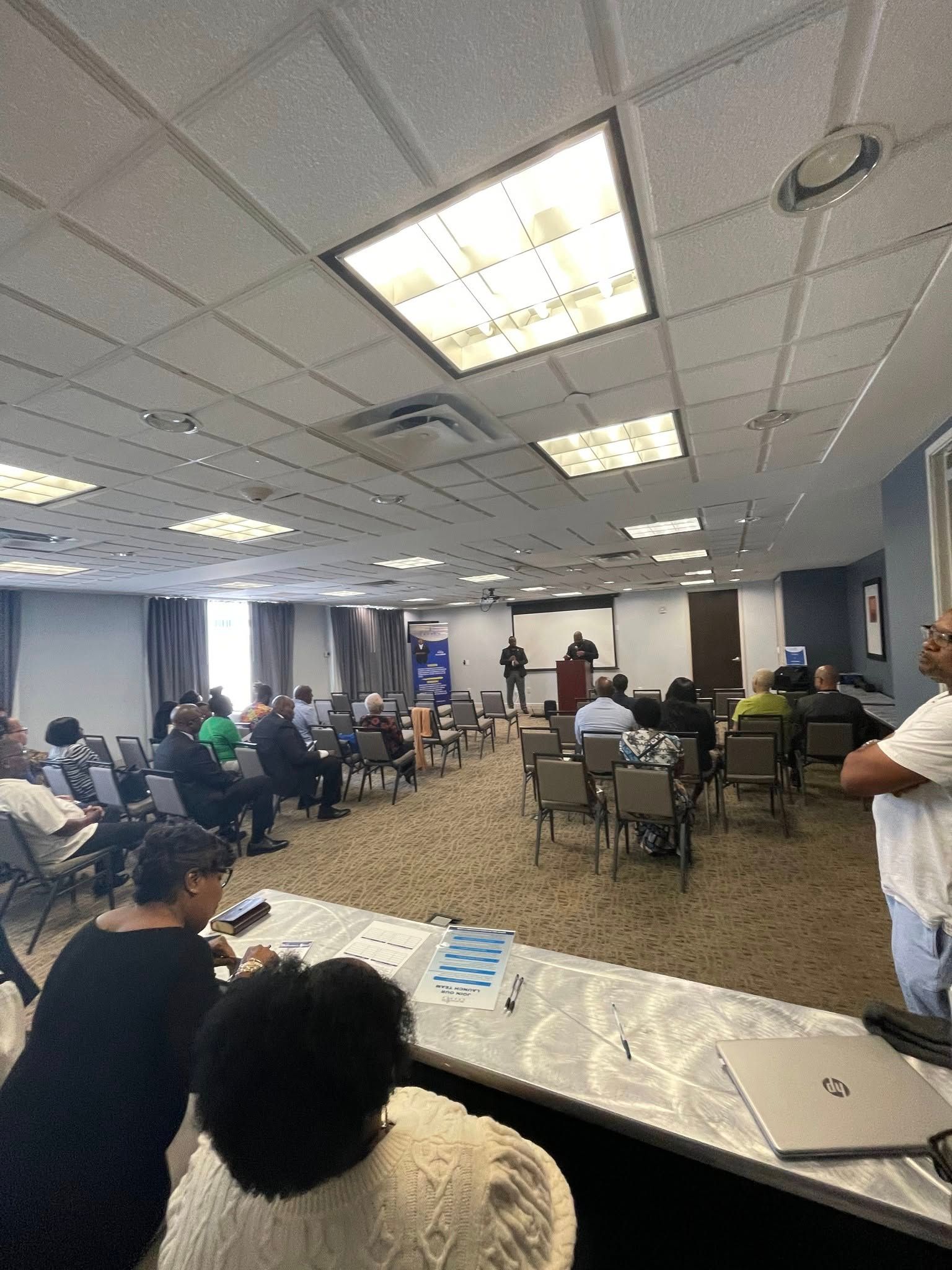 A group of people are sitting in a large room watching a presentation.