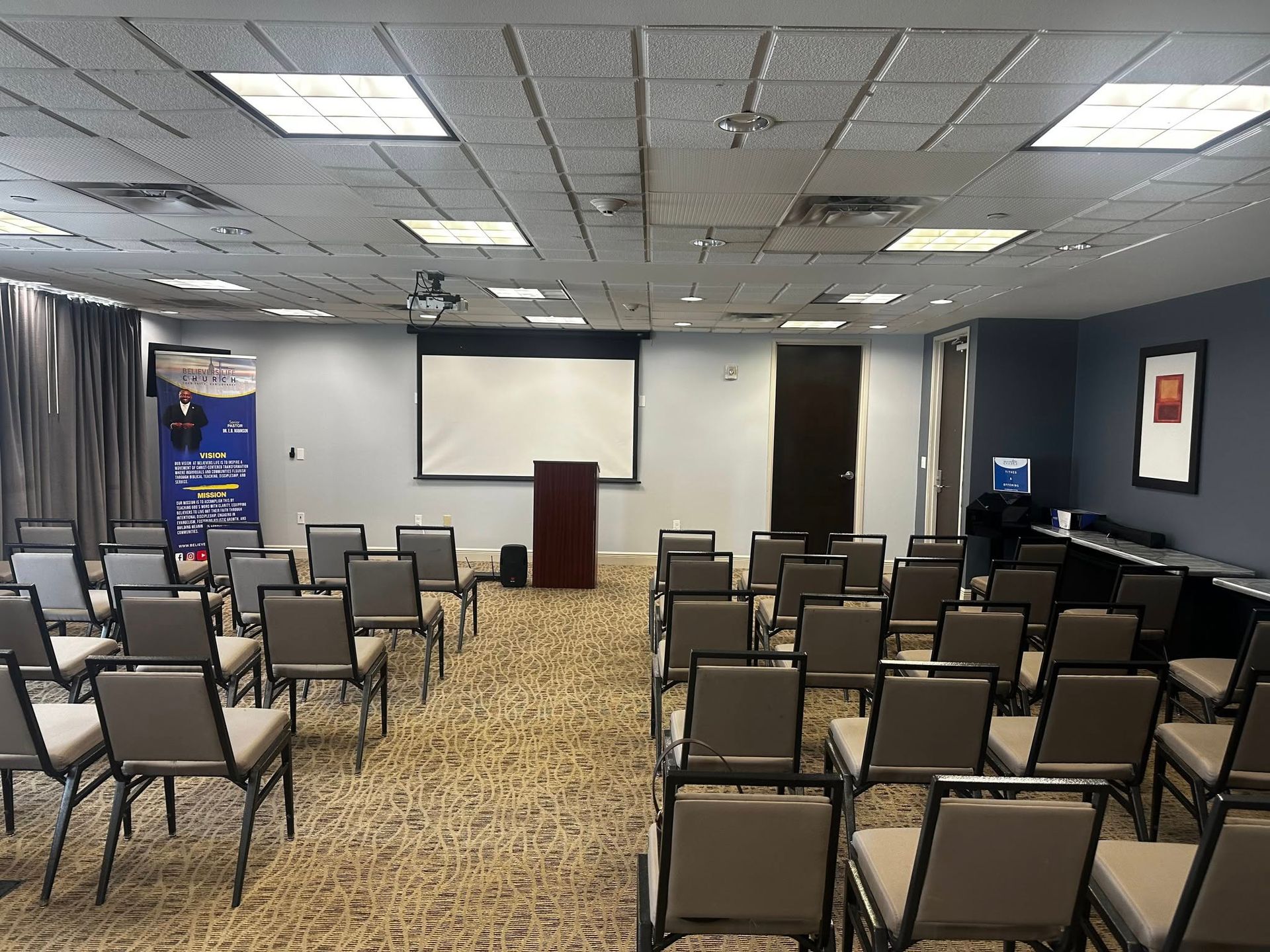 A conference room with rows of chairs and a projector screen.