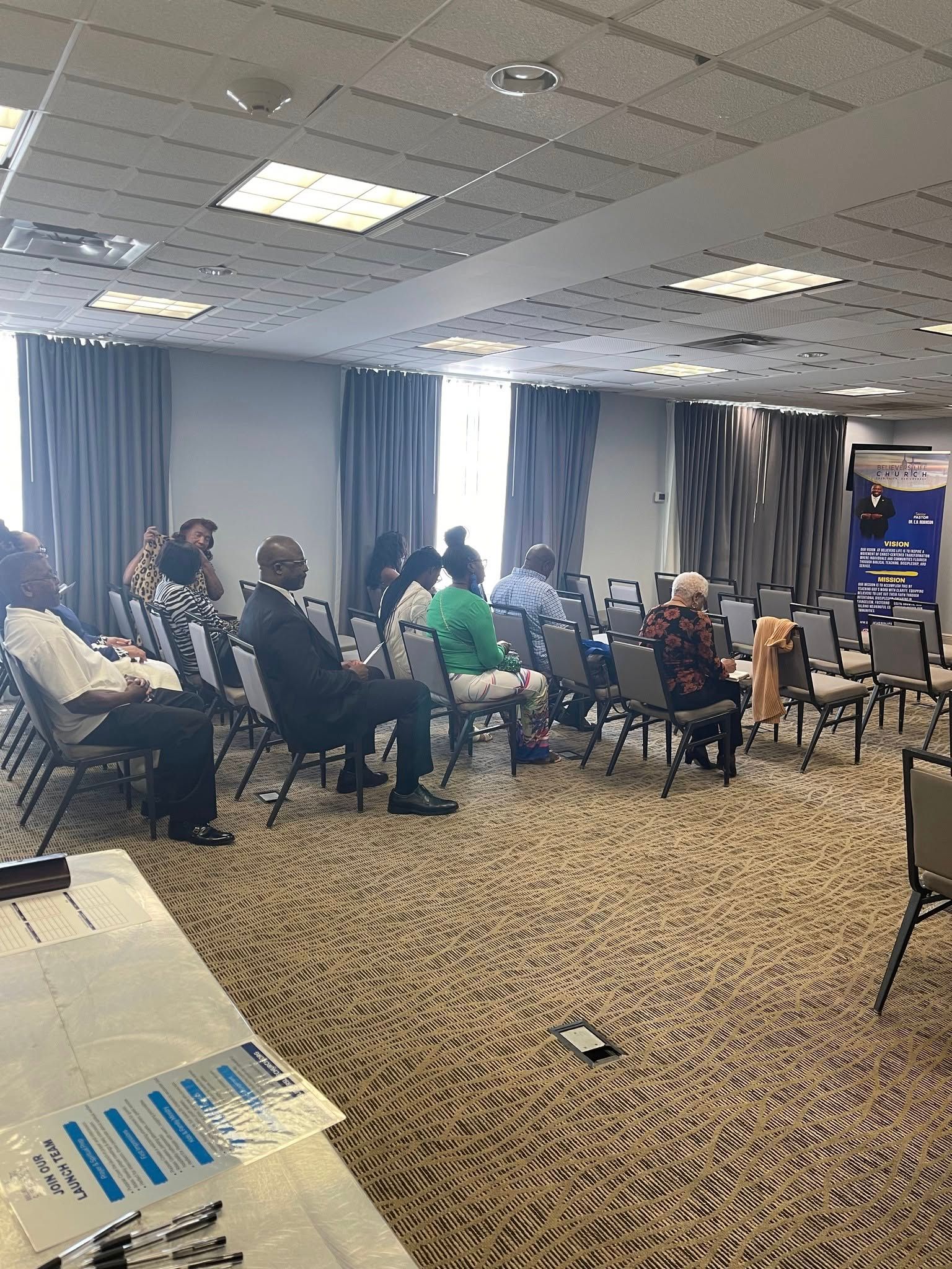 A group of people are sitting in chairs in a large room.