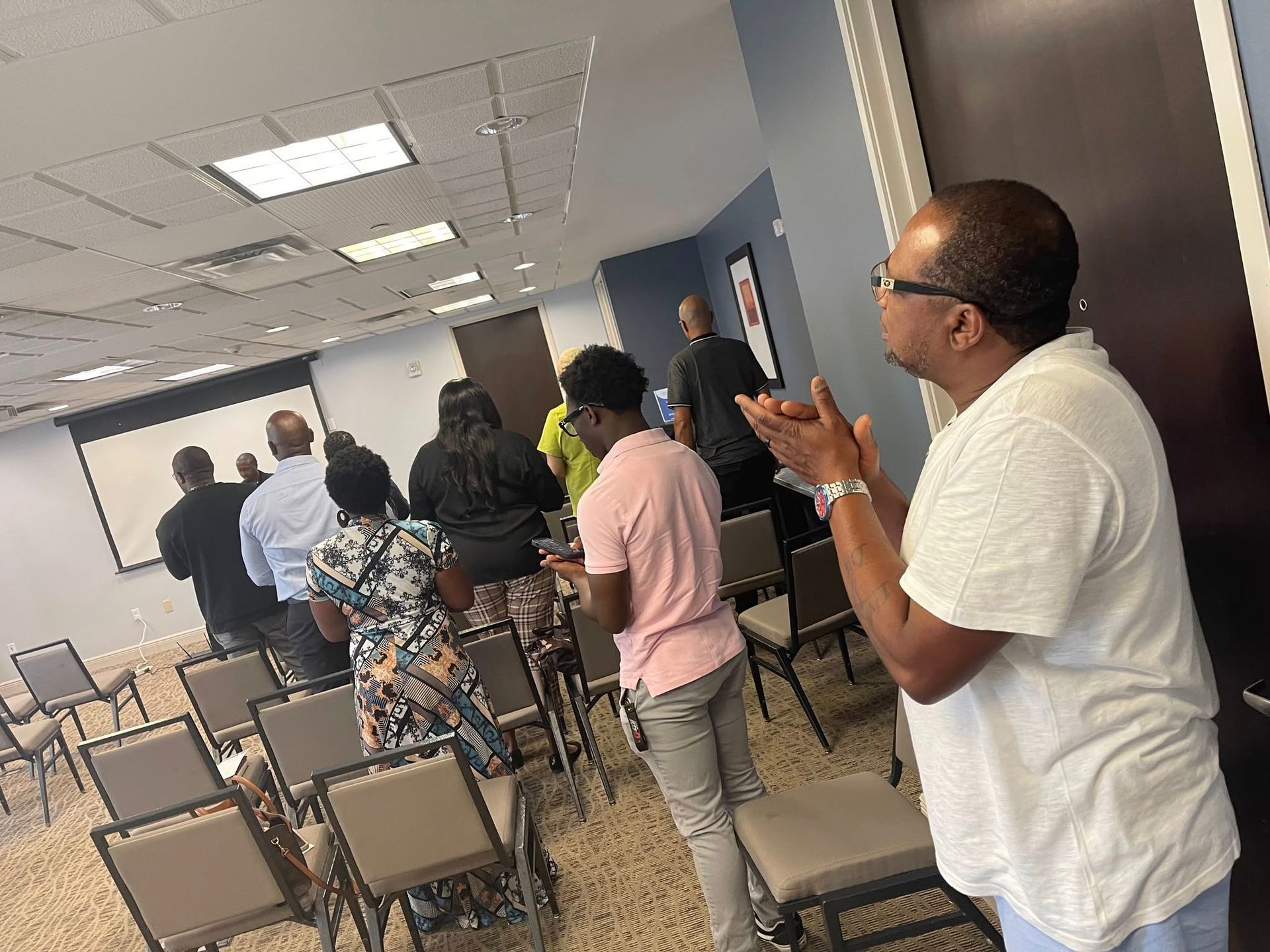A man is standing in front of a group of people in a conference room.