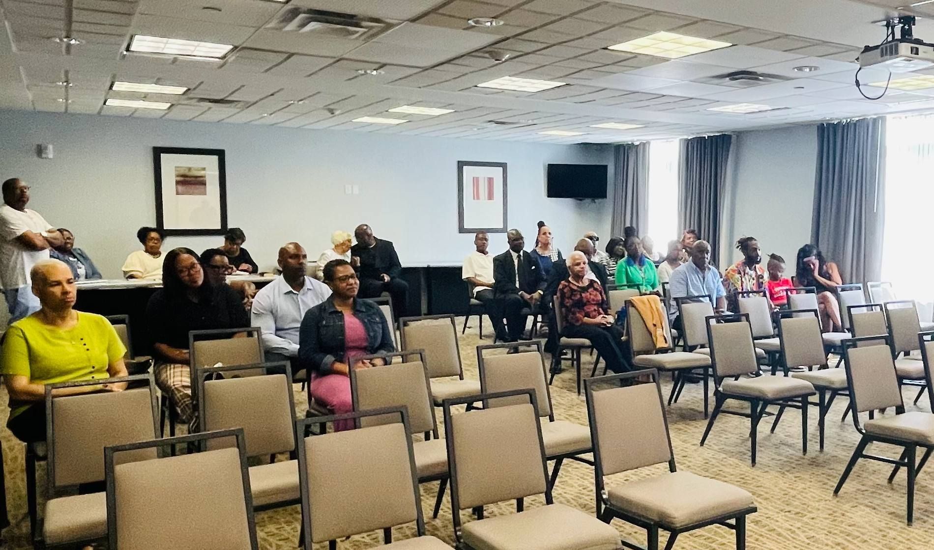 A group of people are sitting in chairs in a conference room.