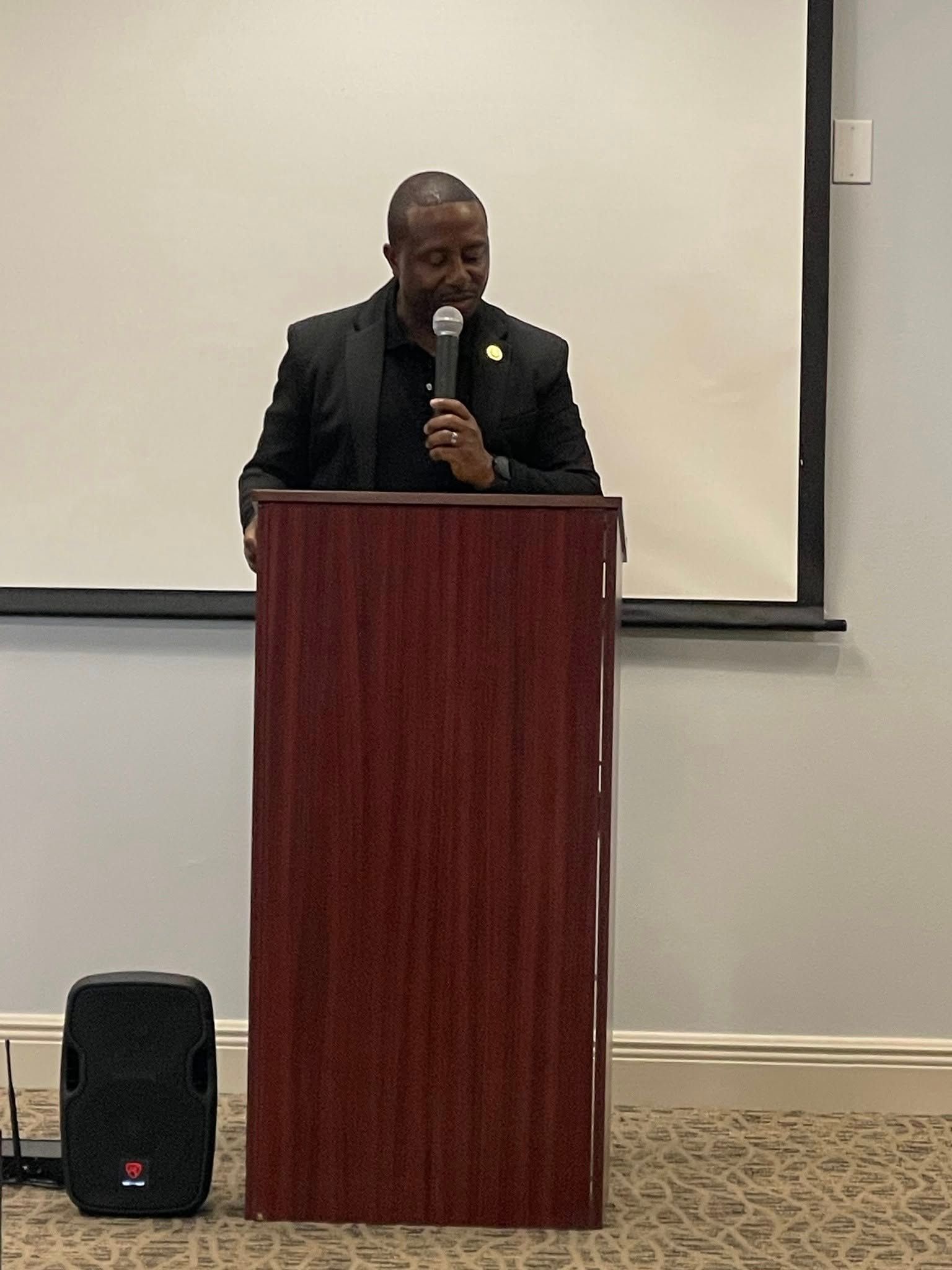 A man is standing at a podium holding a microphone.