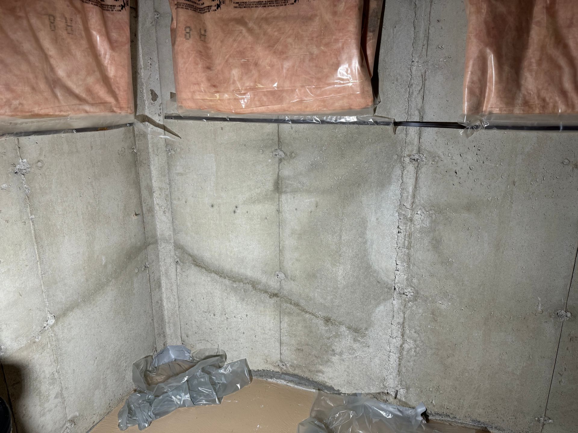 Concrete basement walls with insulation, showing dampness and possible water damage.