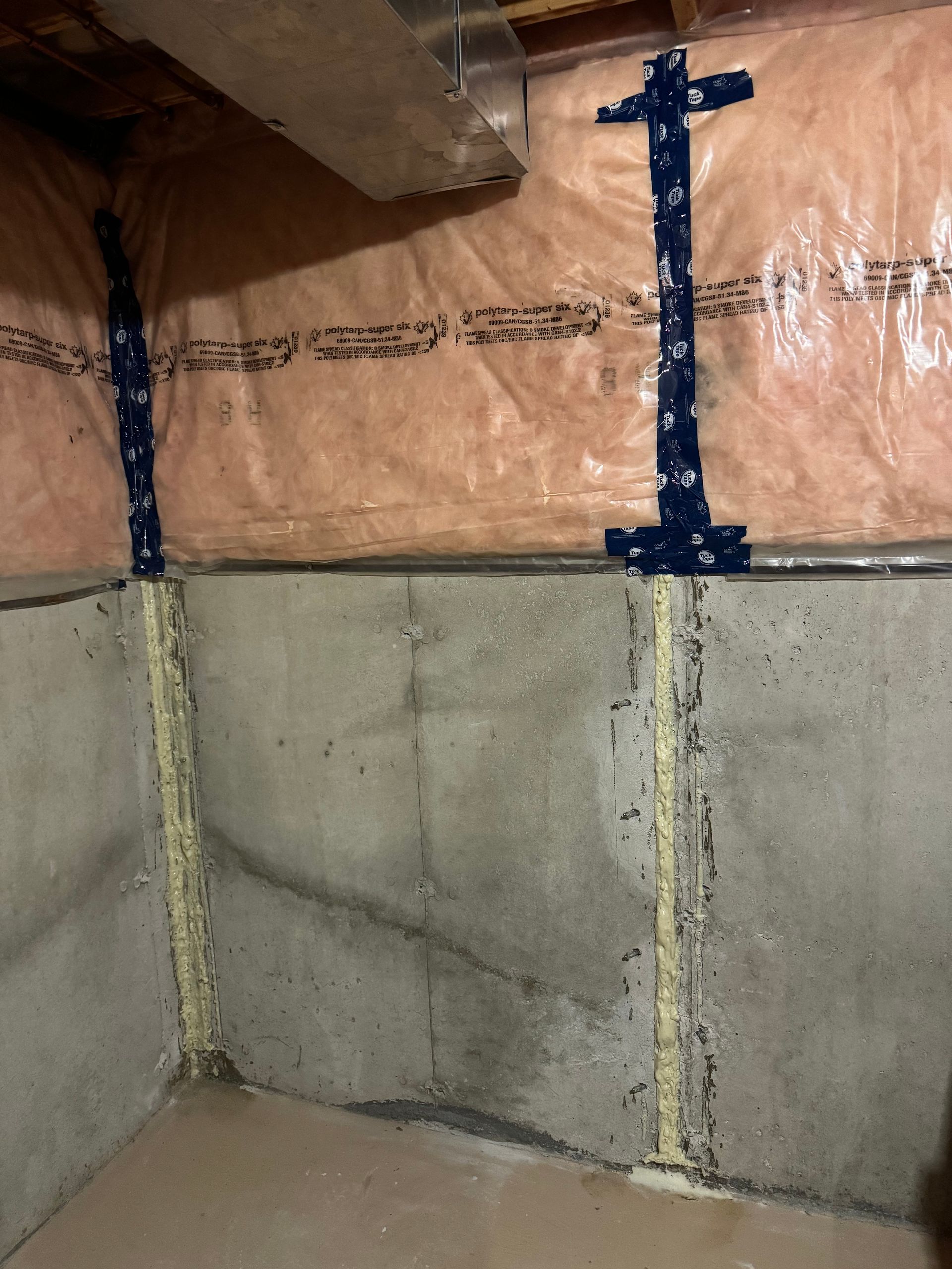 Concrete basement wall with vertical support beams and insulation.