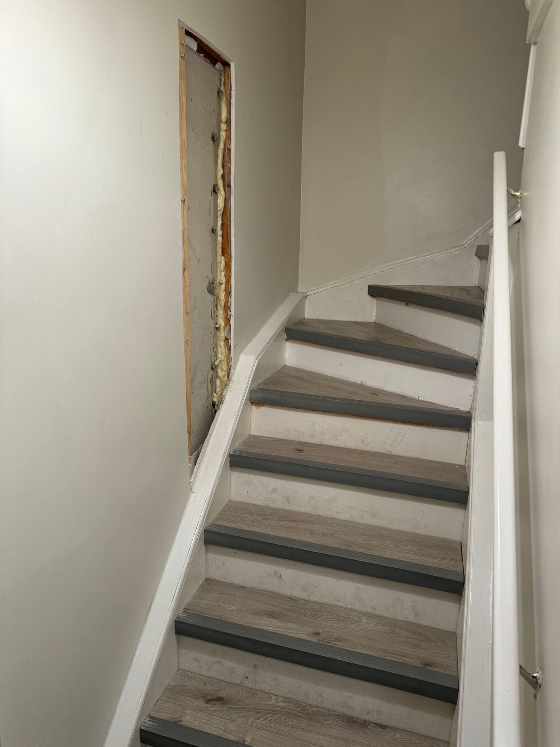 Staircase with white risers, grey treads and a white banister; a doorway is on the left.