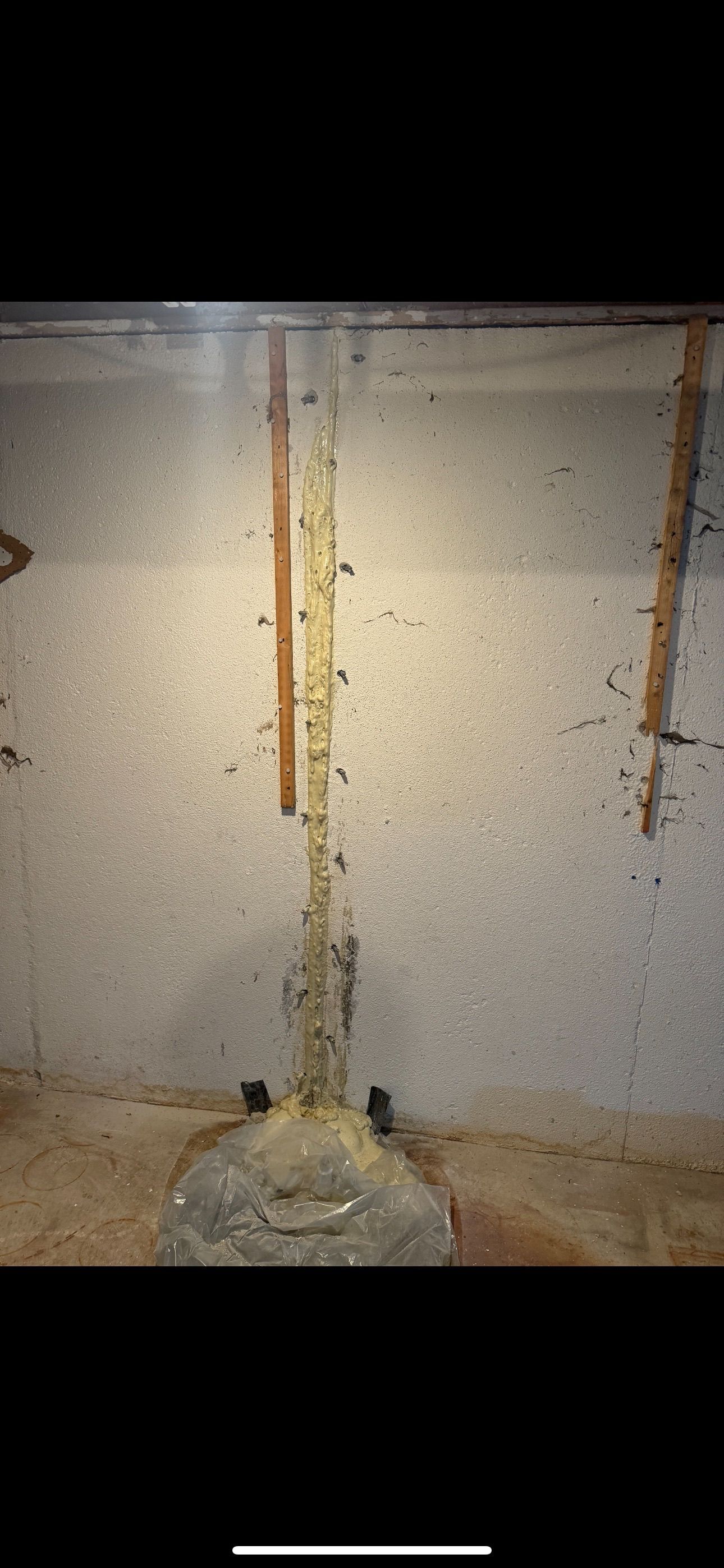 Tall cylindrical structure inside a room with speckled walls. The structure is supported by a large rock-like base.