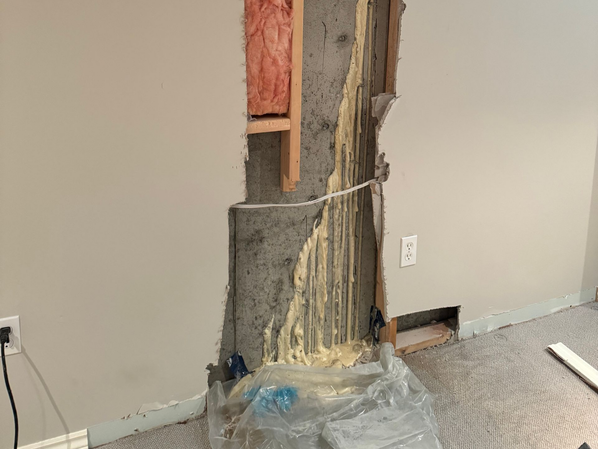 Wall partially demolished, exposing insulation and concrete, with debris on the floor.