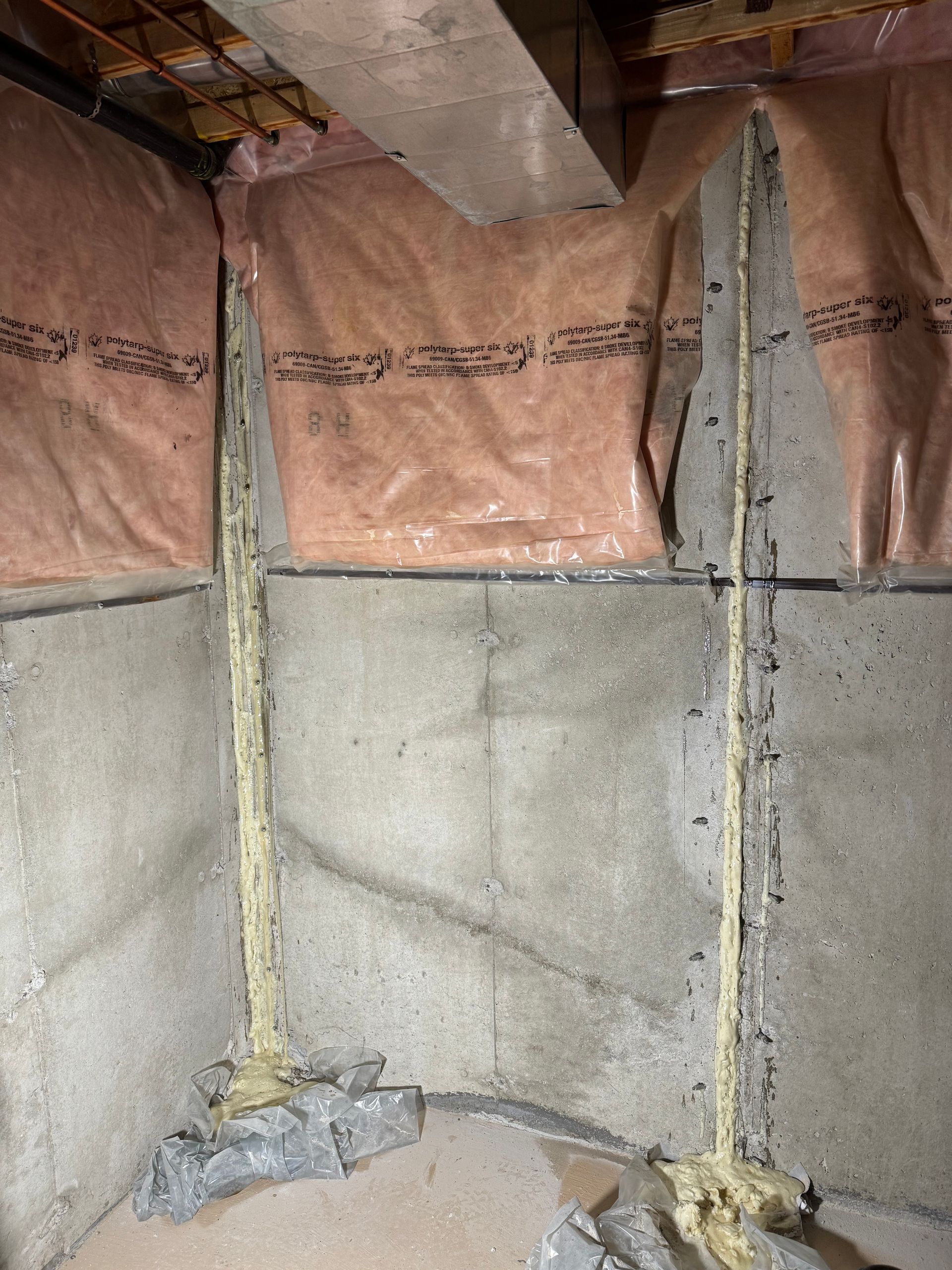 Concrete basement walls with insulation, sealant along cracks.
