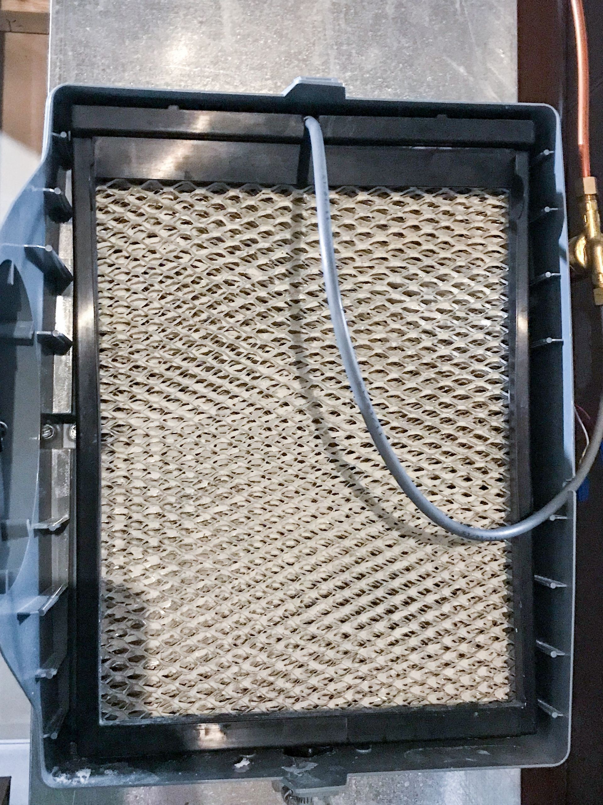 Humidifier filter, honeycomb pattern, black frame, gray cable, in a metal housing.
