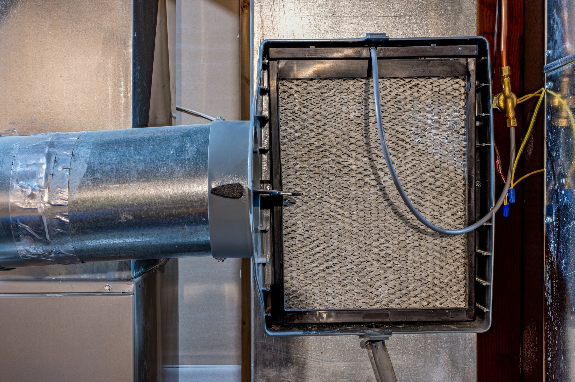 Humidifier attached to HVAC duct, showing absorbent pad and wiring.