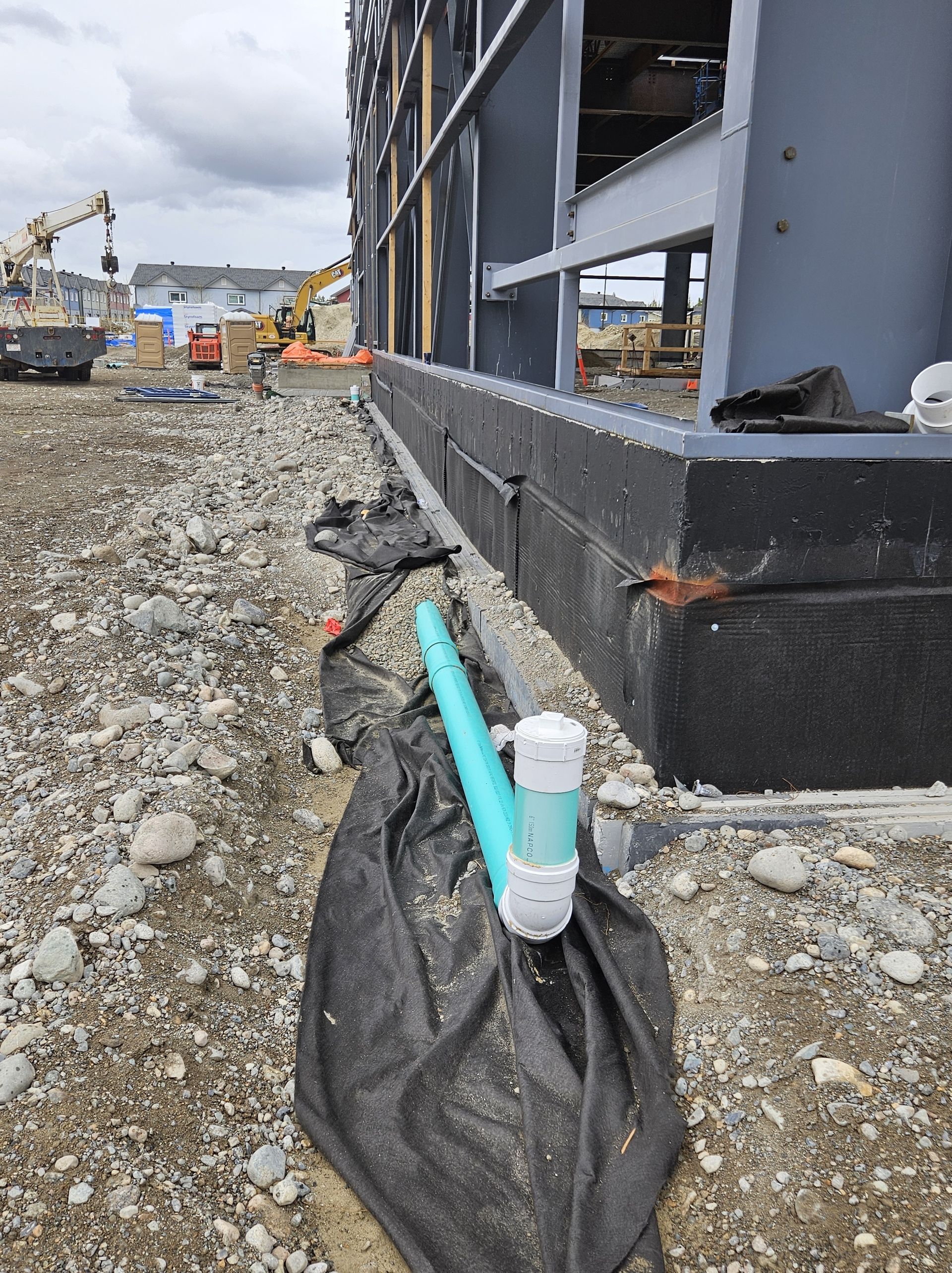 Construction site with a blue pipe, drainage system, and building foundation.