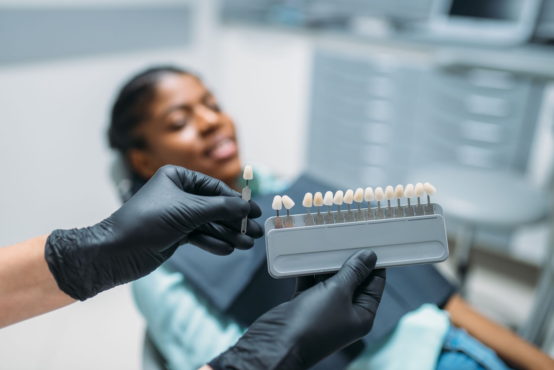 A woman is sitting in a dental chair while a dentist is holding a model of teeth.