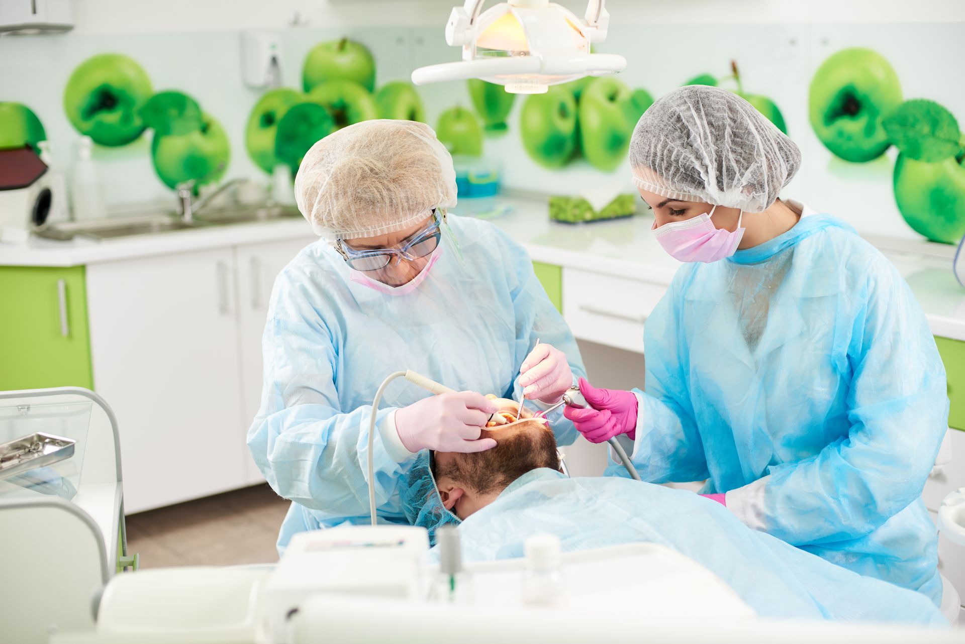 Two dentists are examining a patient 's teeth in a dental office.