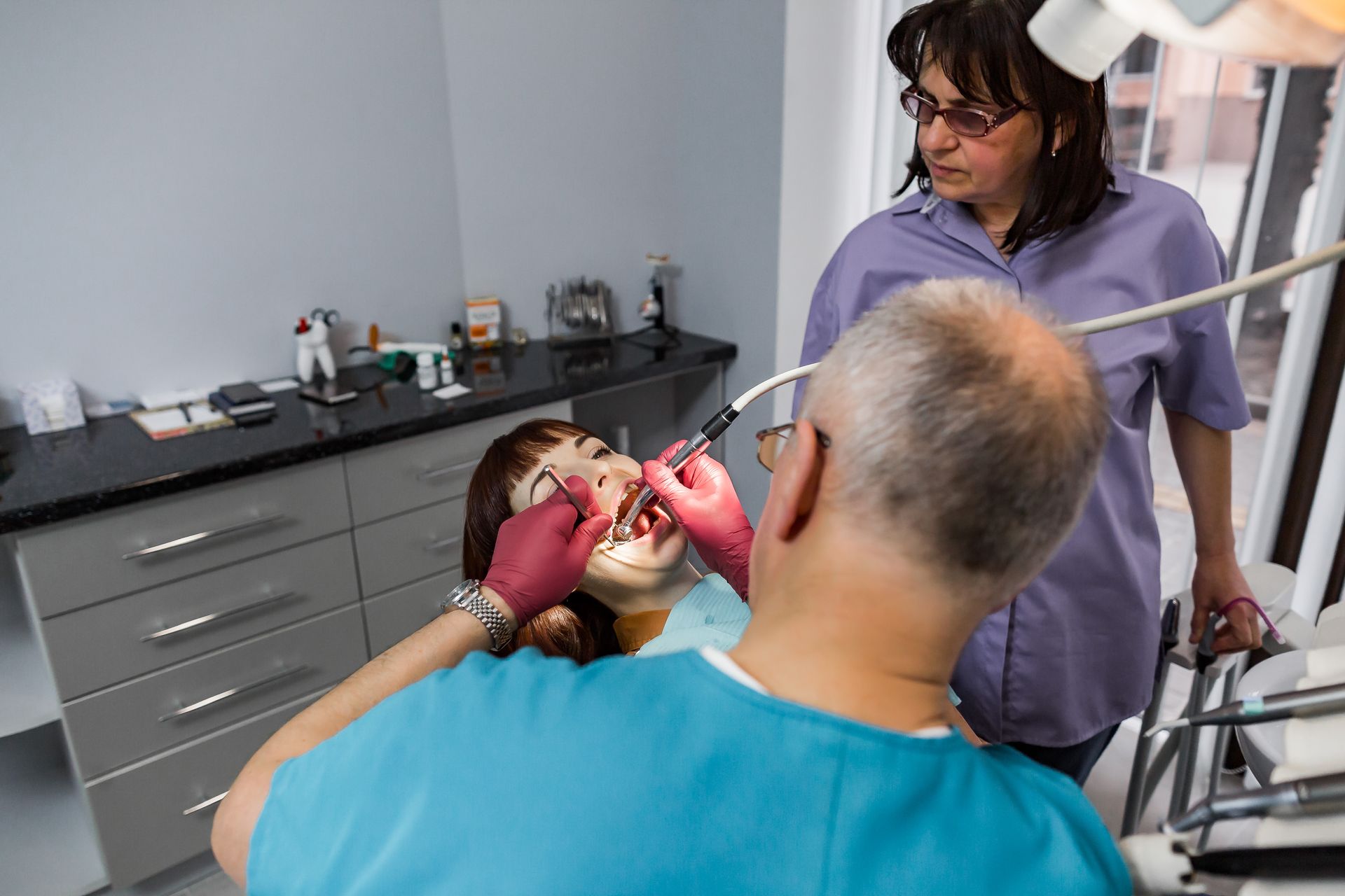 A woman is getting her teeth examined by a dentist in a dental office.