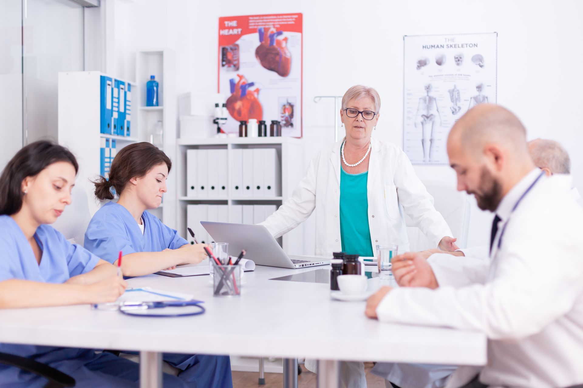 A group of doctors and nurses are sitting around a table having a meeting.