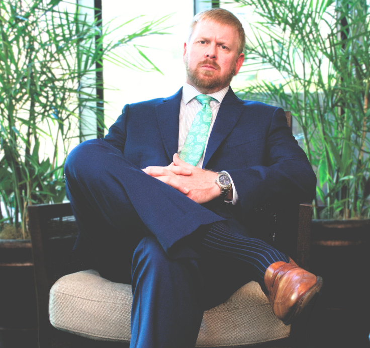 Male Personal Injury Lawyer in a suit and tie is sitting in a chair with his arms crossed