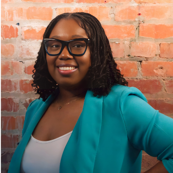 A woman in a striped dress is sitting in a chair with her legs crossed.