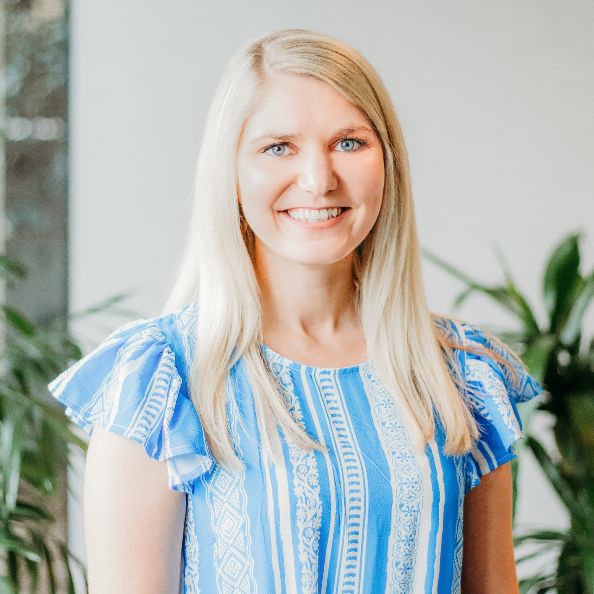 A woman in a blue and white striped shirt is smiling for the camera.